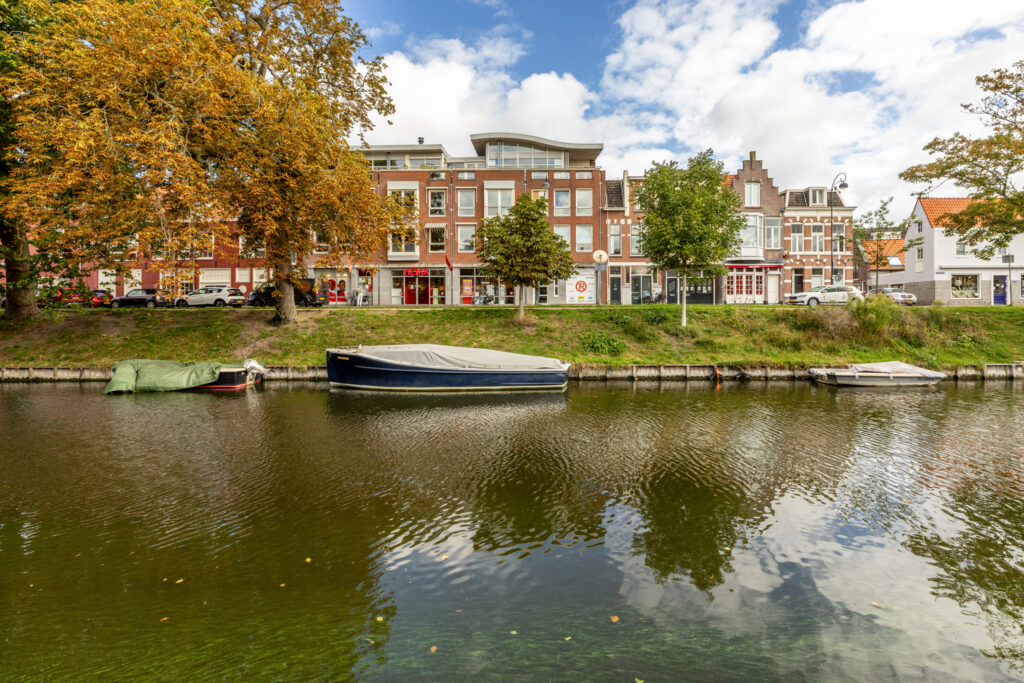 Canal-side buildings with boats, autumn trees.