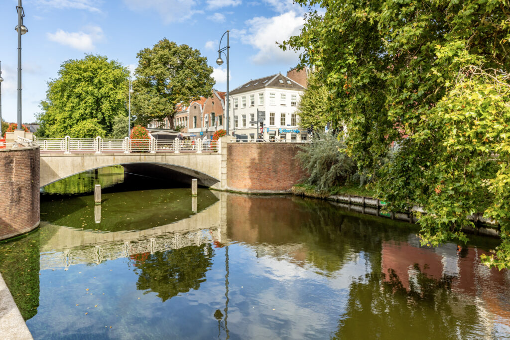 Scenic bridge over tranquil canal with reflection.