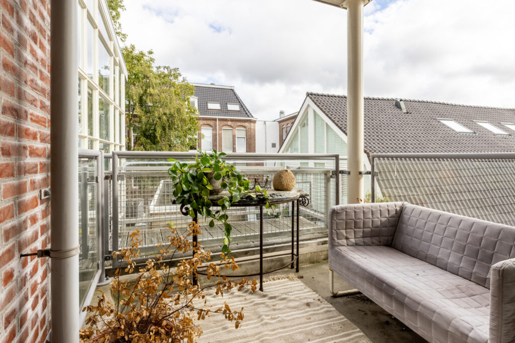Cozy balcony with plants, sofa, and city view.