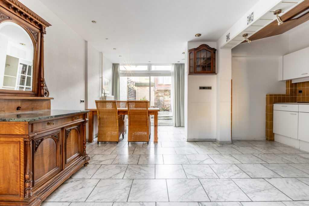 Spacious dining area with wooden furniture and marble floor.