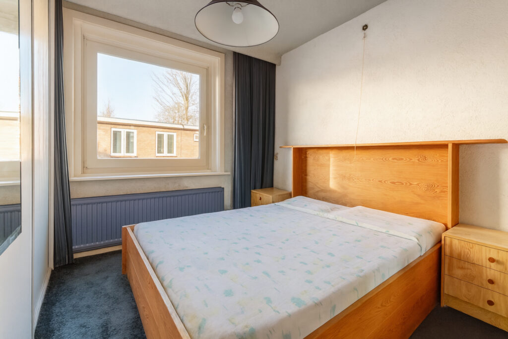 Minimalist bedroom with large window and wooden bed.