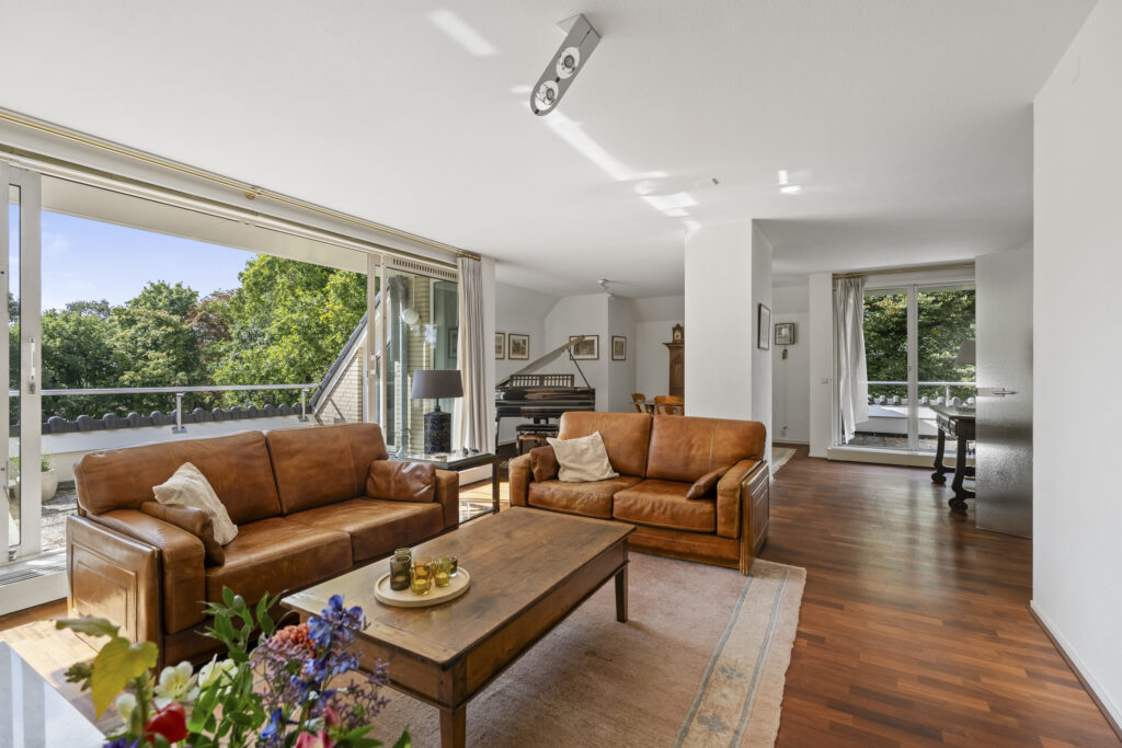 Bright living room with leather couches and piano.