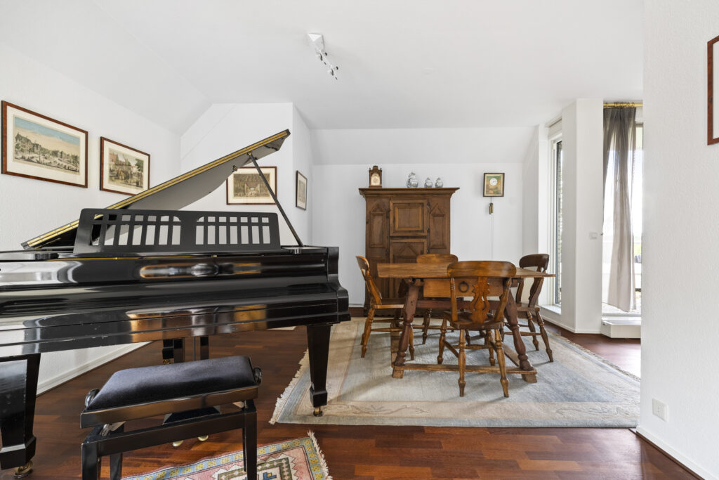 Elegant room with grand piano and dining table.
