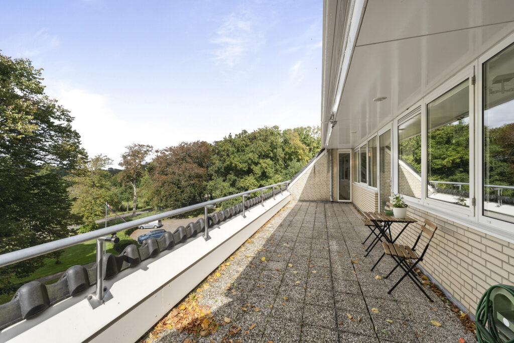Spacious balcony with forest view and outdoor seating.