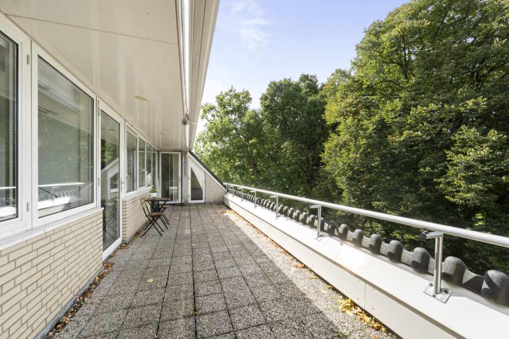 Spacious balcony overlooking green trees and nature.