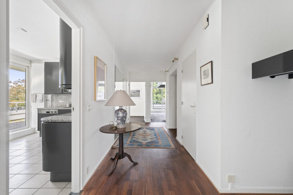 Bright hallway with wooden floor and side table lamp.