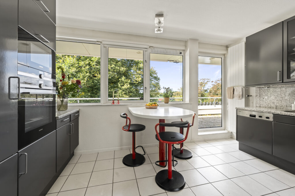 Modern kitchen with black cabinets and large windows.