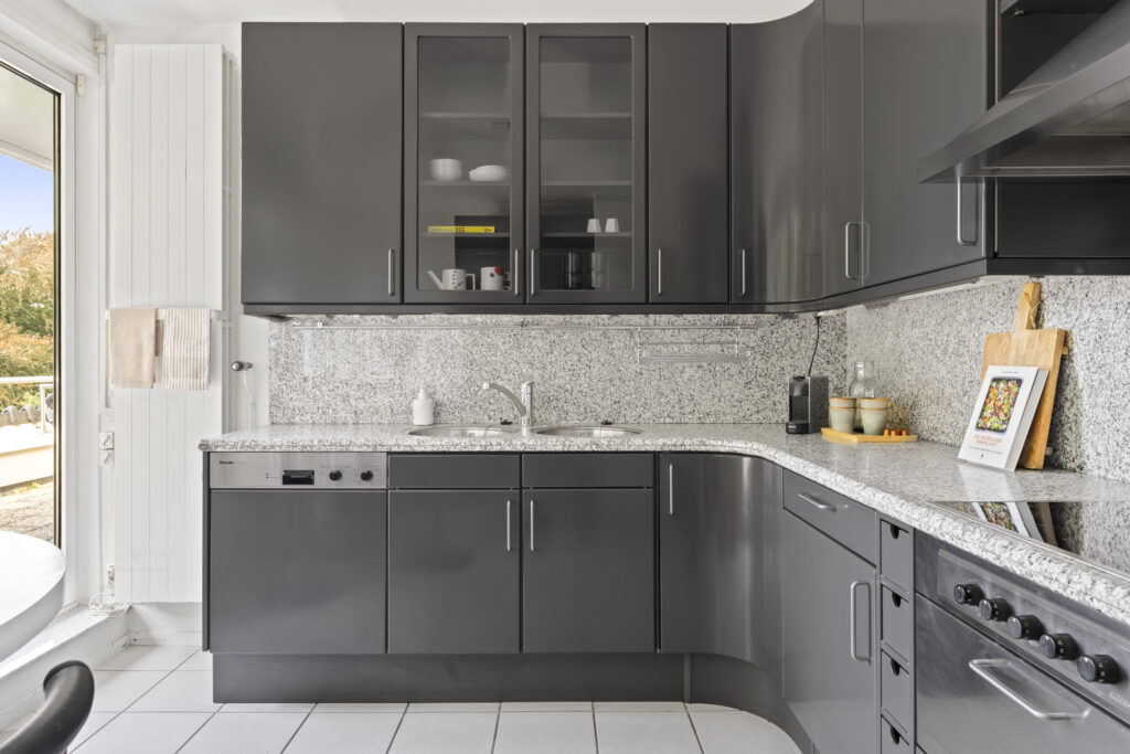 Modern kitchen with gray cabinets and granite countertops.