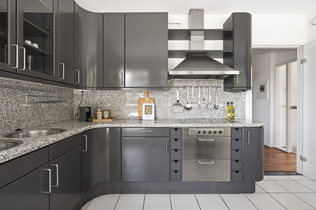Modern kitchen with gray cabinets and granite countertops.