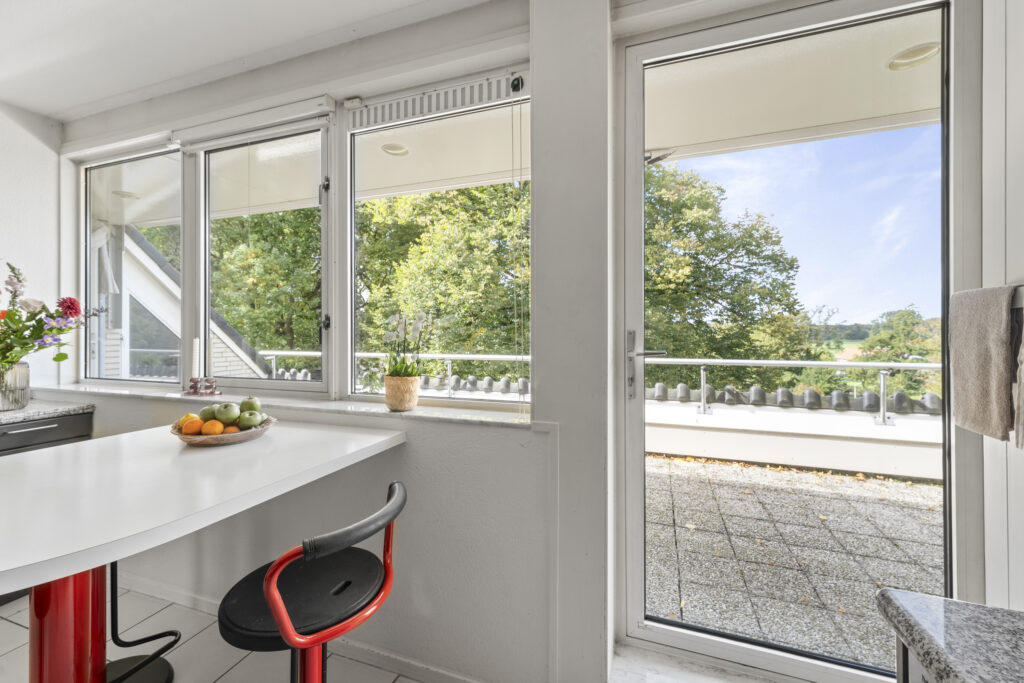 Bright kitchen with large windows and balcony view.