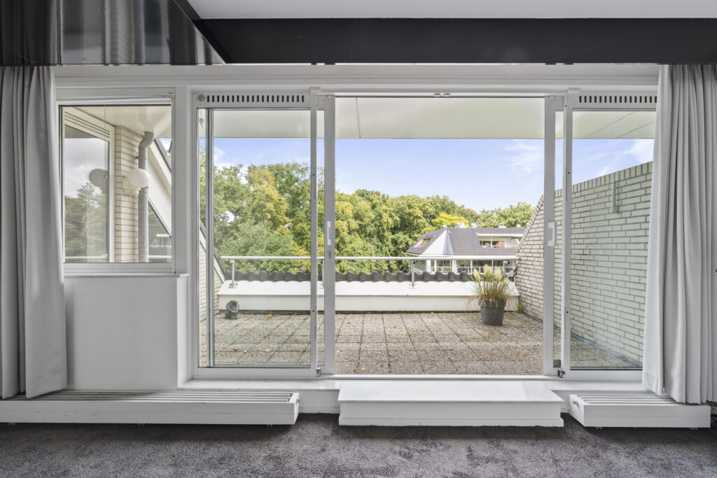 Spacious balcony view with greenery in background.