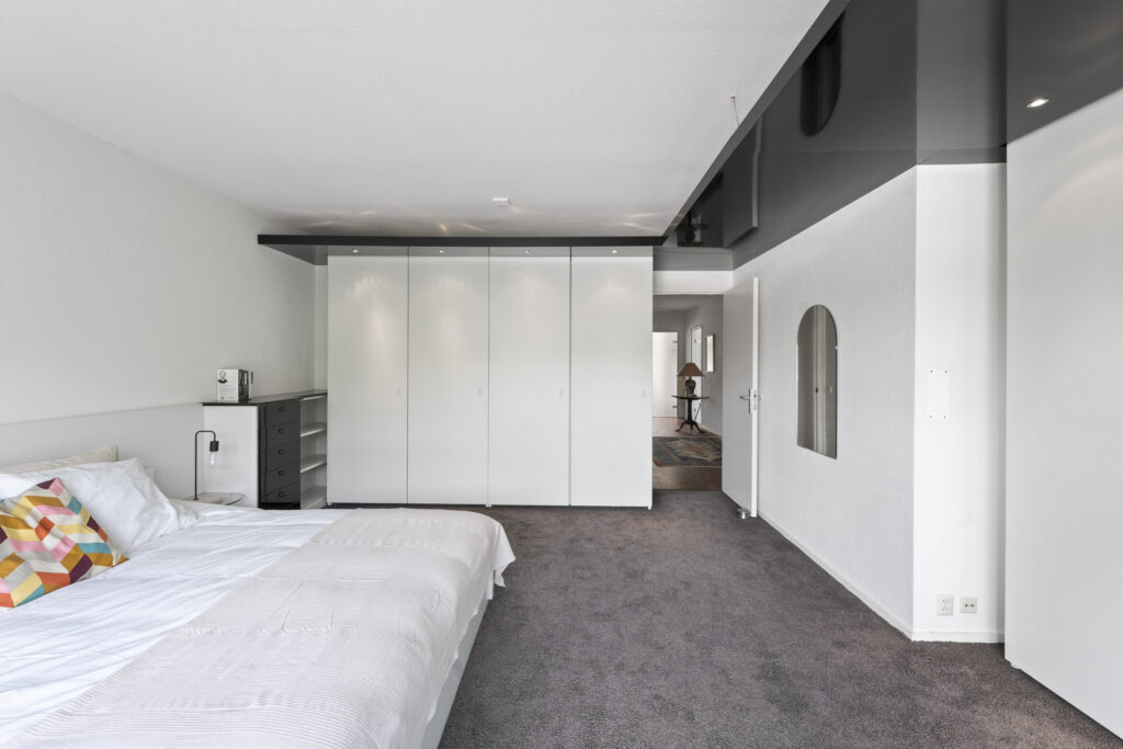 Modern bedroom with large white wardrobe and bed