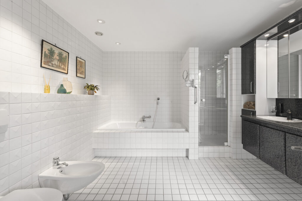 Modern bathroom with white tiles and black cabinets.