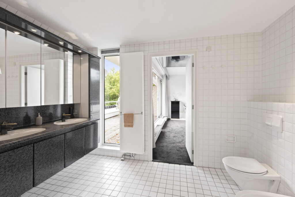 Modern white tiled bathroom with double sinks.