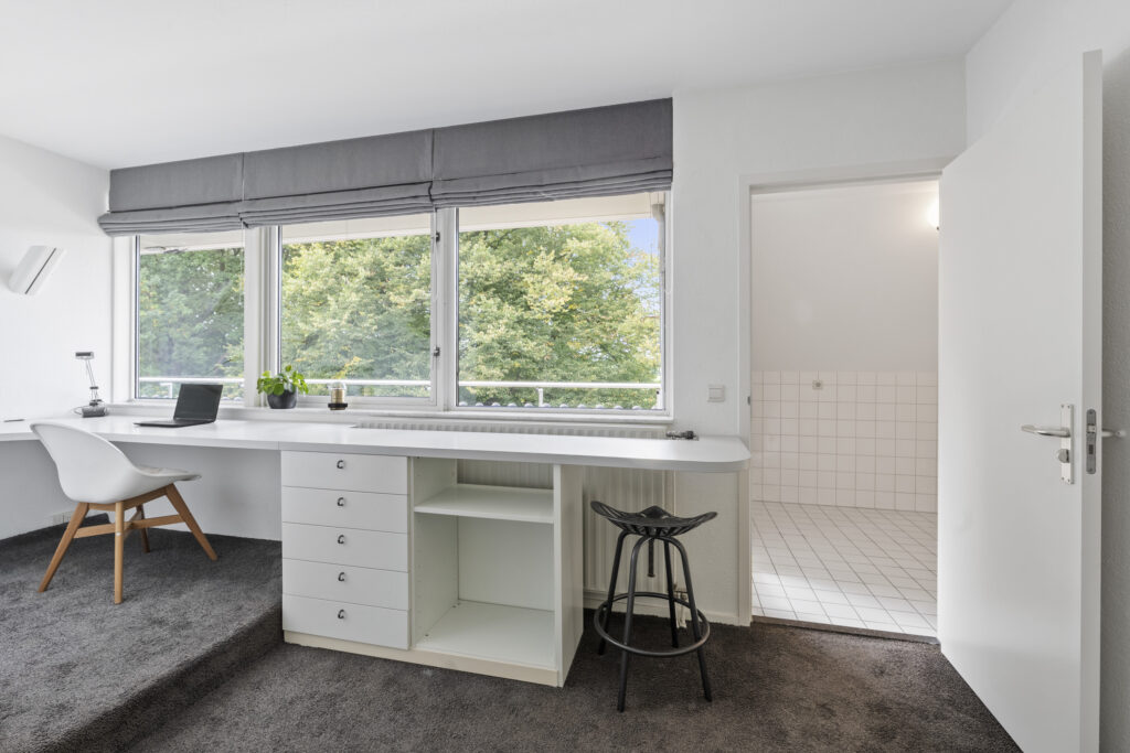 Modern home office with large windows and desk.