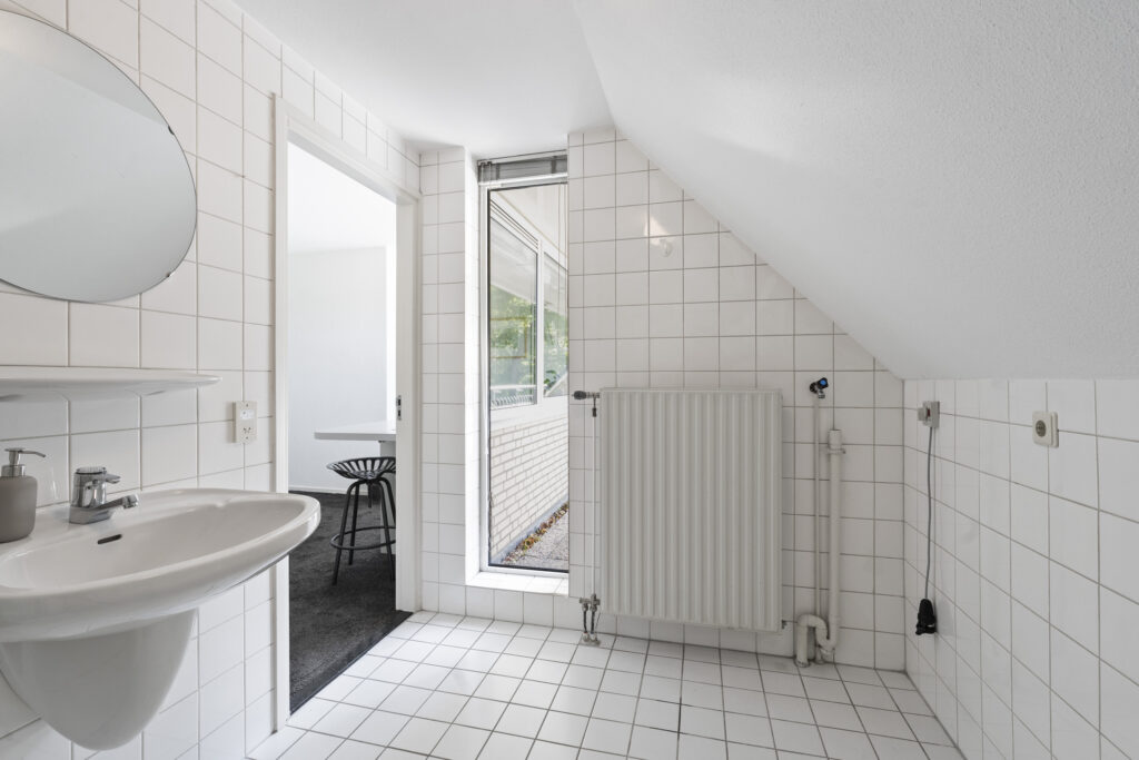 Modern white-tiled minimalist bathroom corner view