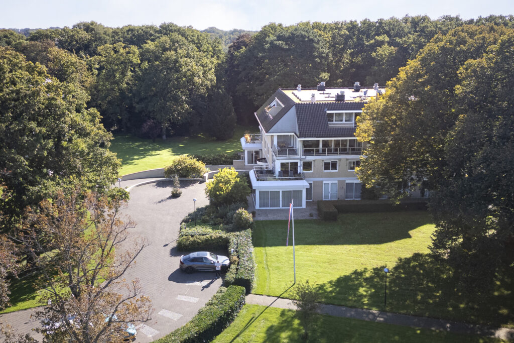 Large house surrounded by trees and greenery.