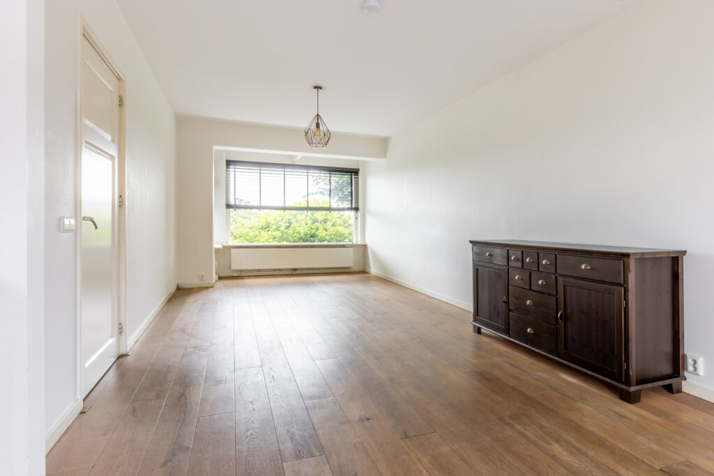 Empty living room with wooden floors and sideboard.