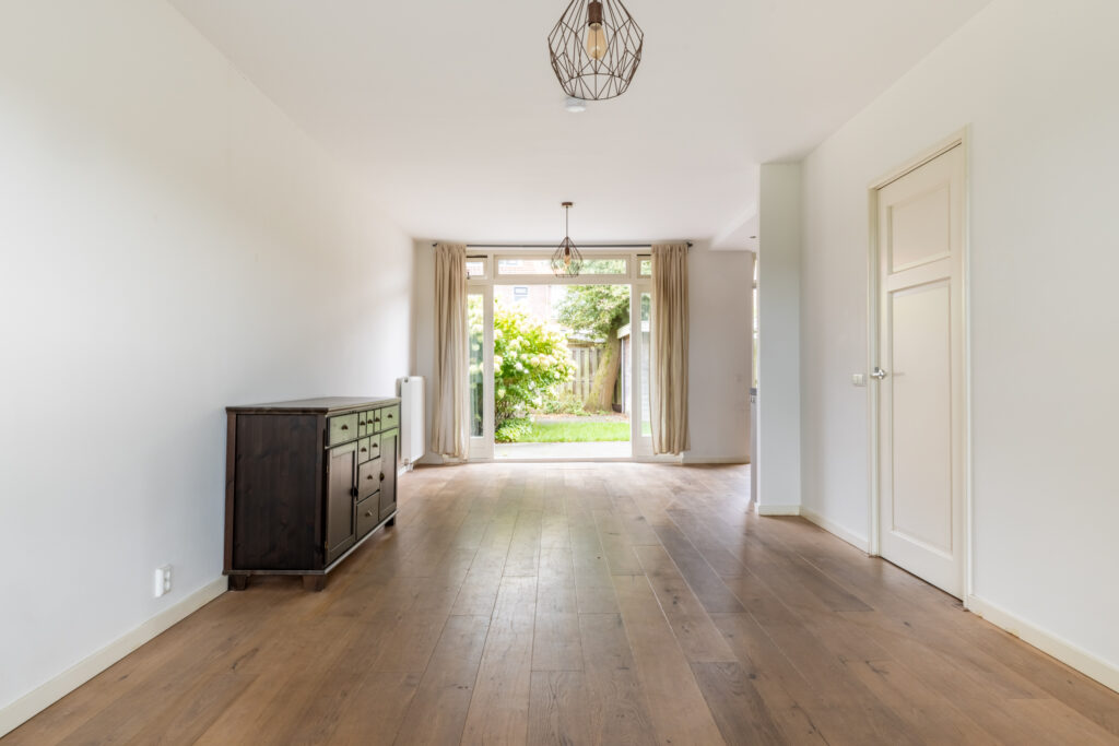 Spacious room with wooden flooring and garden view.