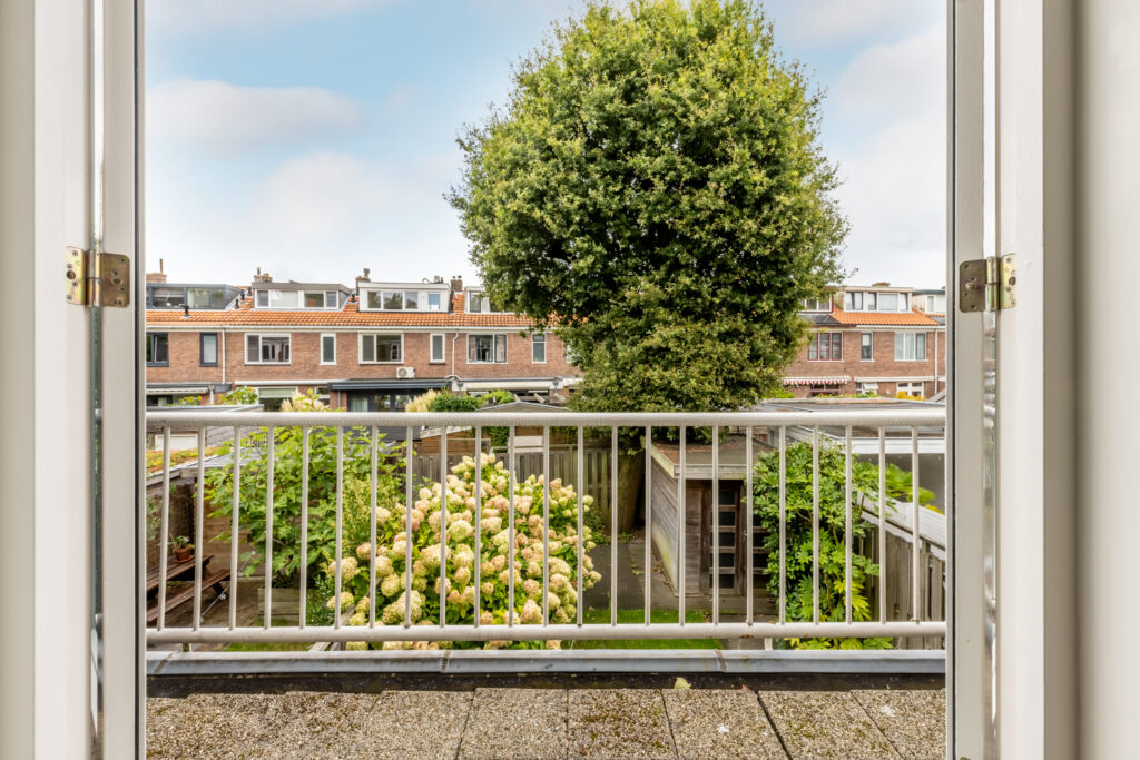 Garden view from balcony with tree and flowers.