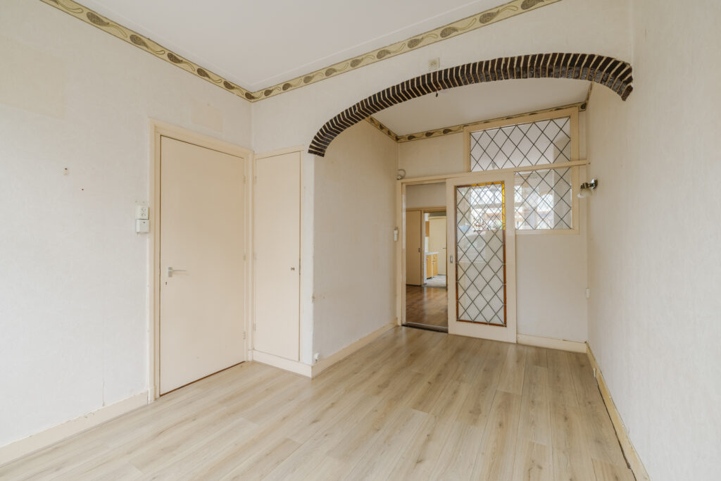 Empty room with wooden floor and patterned glass doors.