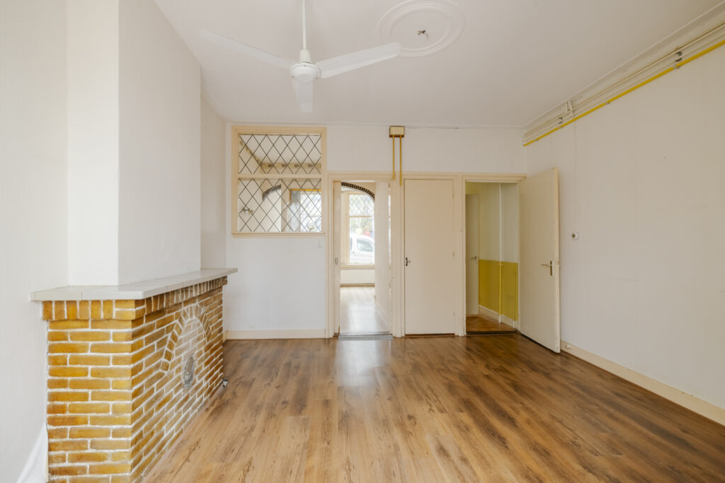 Empty room with wood floor and brick fireplace.