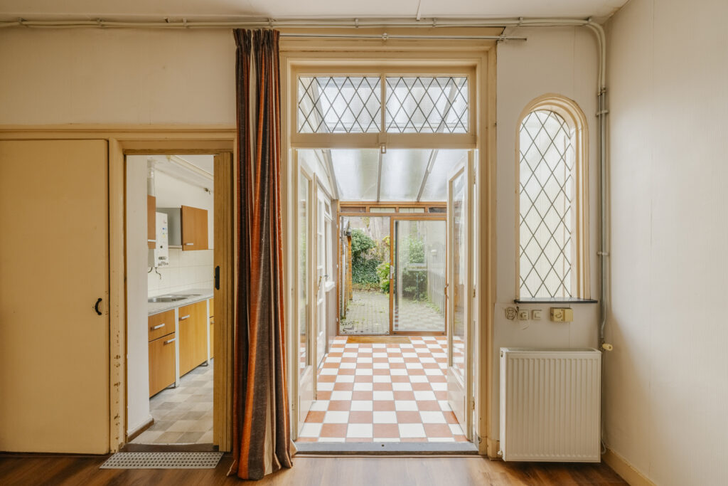 Open sunroom with checkered tile floor and garden view.