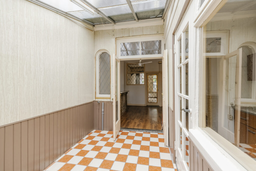 Enclosed porch with checkered floor tiles.
