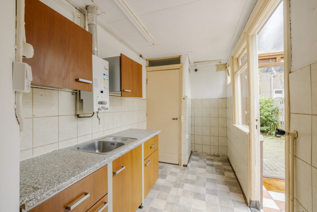 Small kitchen with wooden cabinets and tiled floor.
