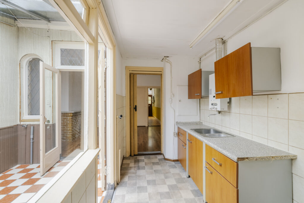 Narrow kitchen with wooden cabinets and outside view.