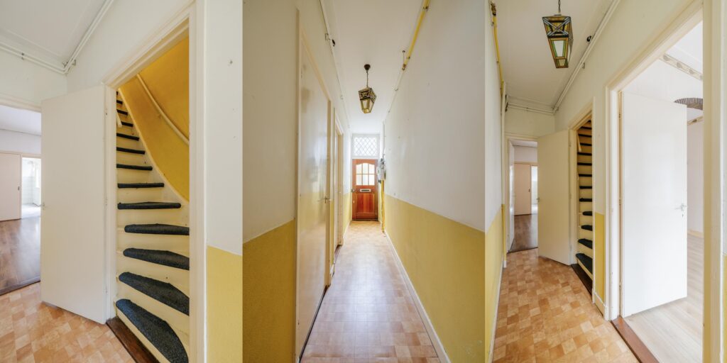 Interior hallway with yellow staircase and doors.