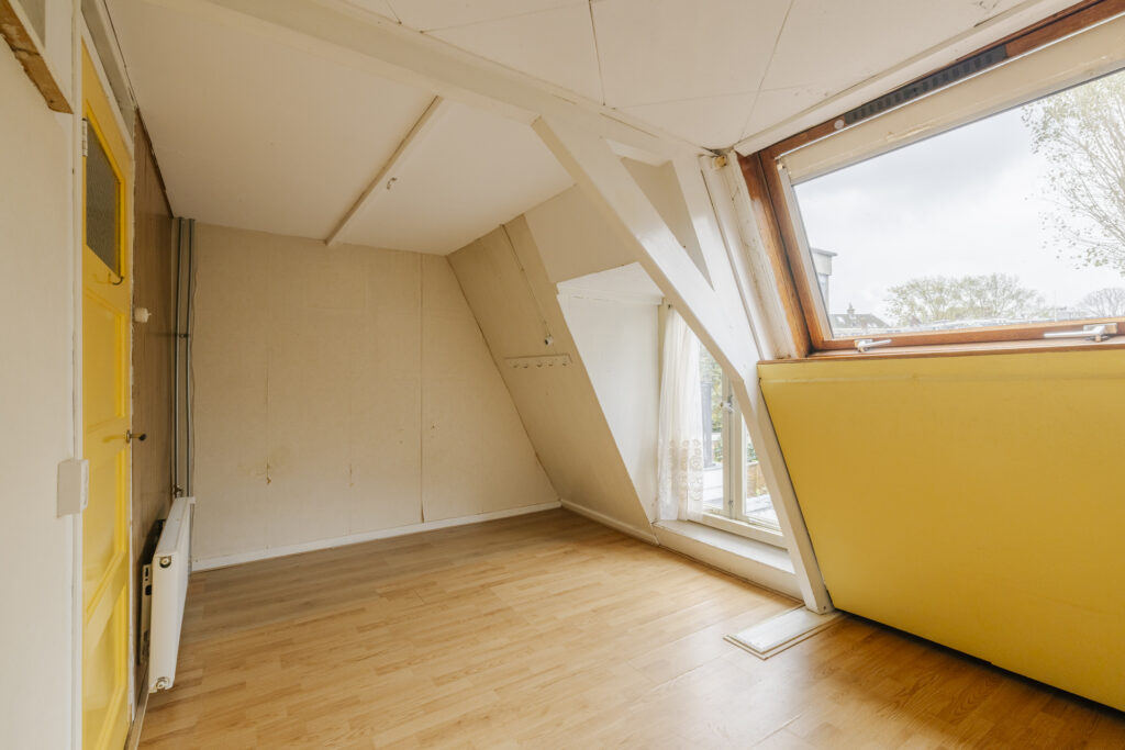 Bright attic room with wooden flooring and skylight.