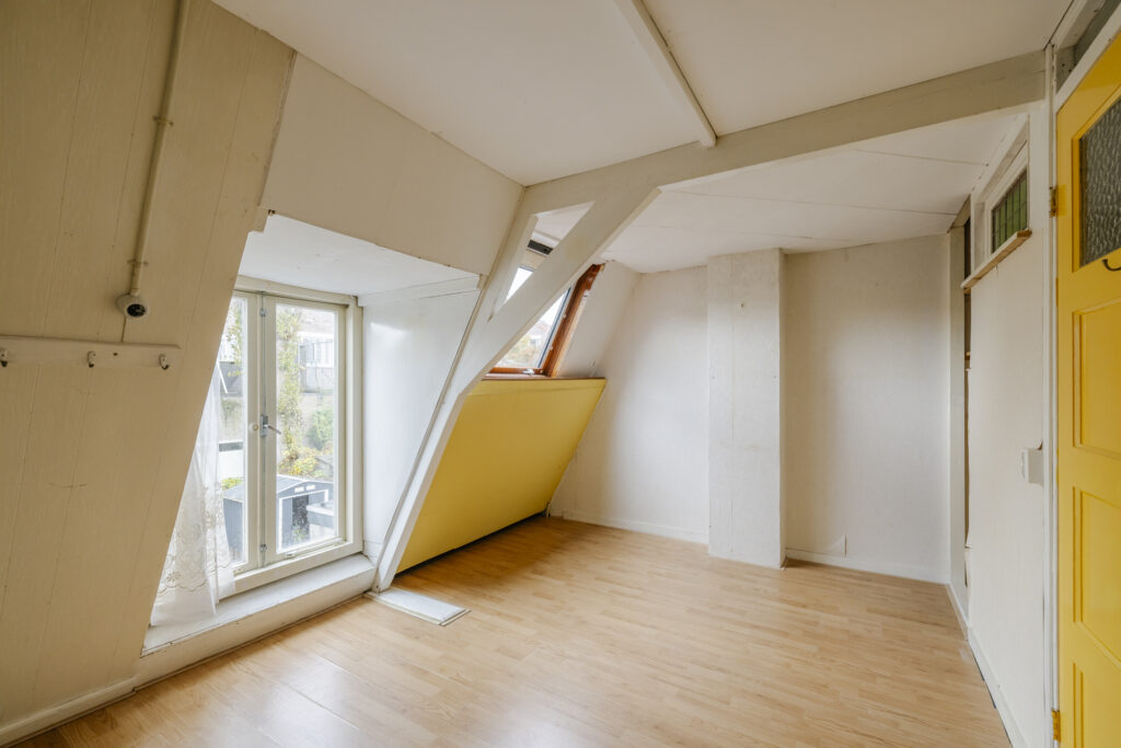 Bright attic room with wooden floor and yellow door.