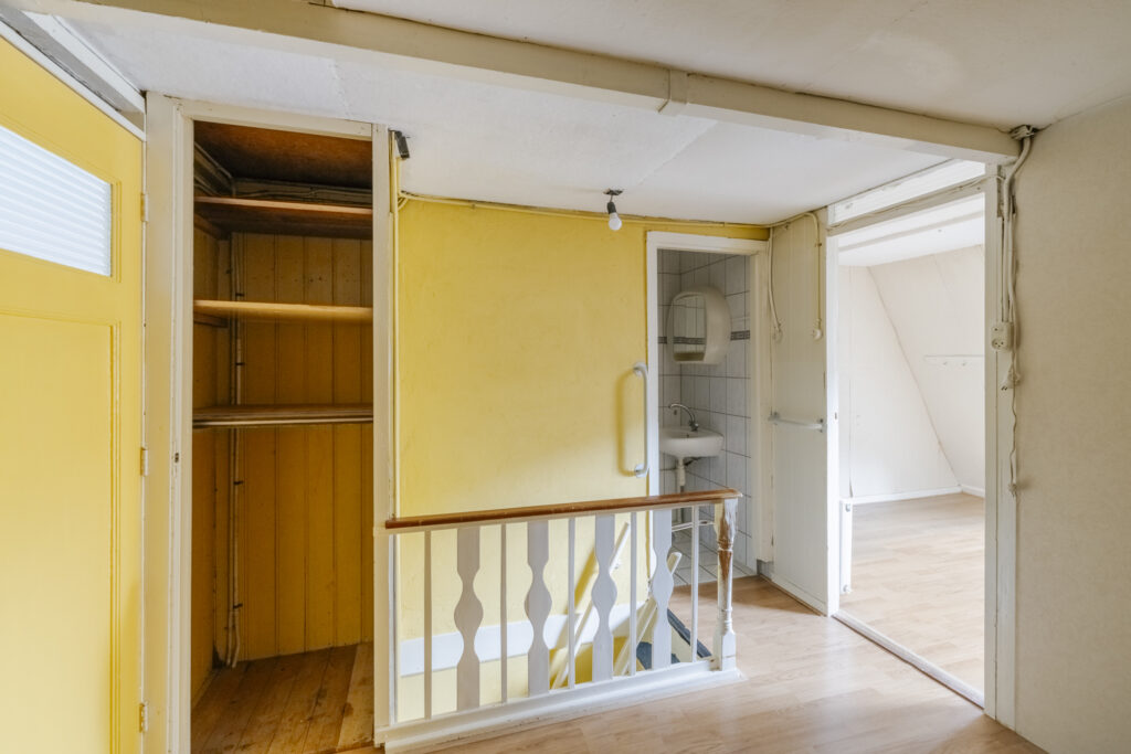 Interior with staircase, yellow walls, and small bathroom.