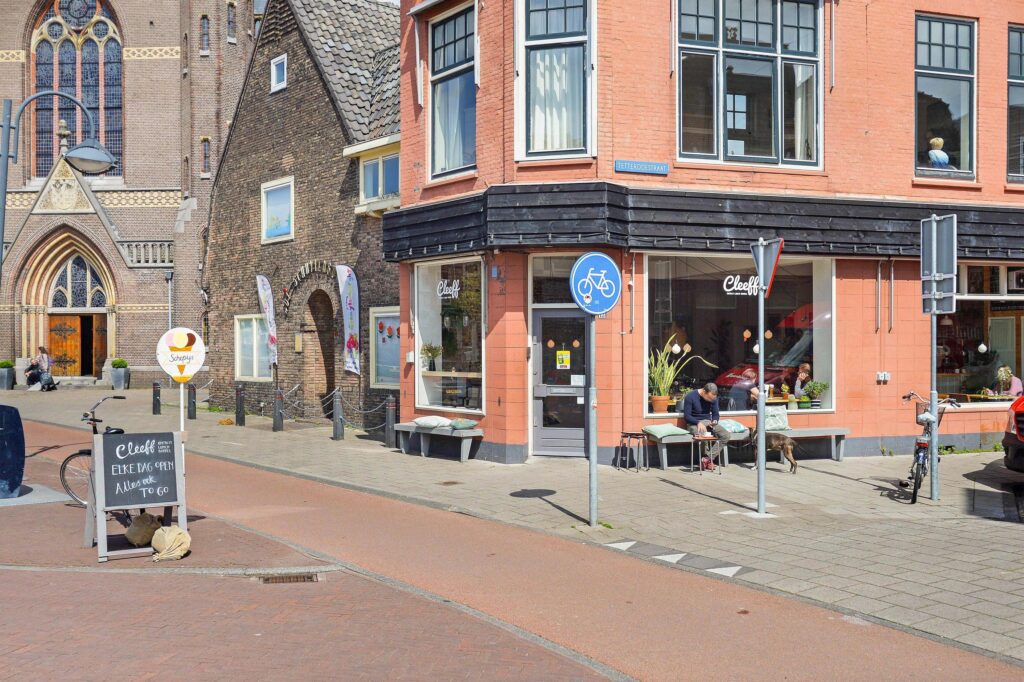 Corner cafe exterior with bicycles and pedestrians.