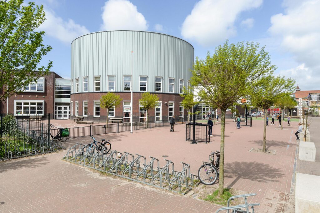 Modern school building with bicycle racks and trees.