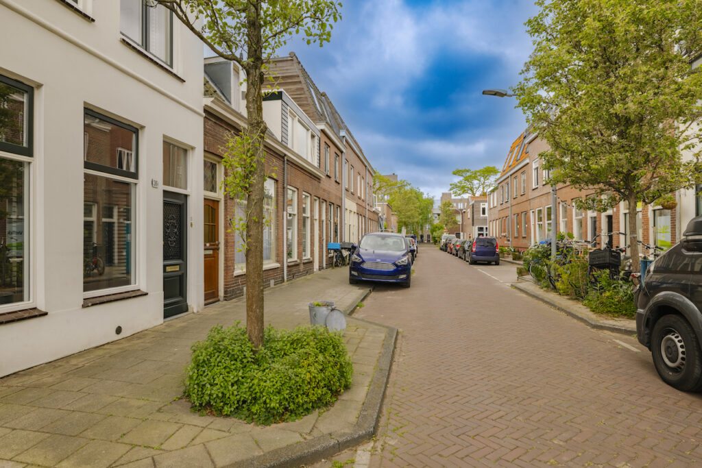 Residential street with parked cars and trees.