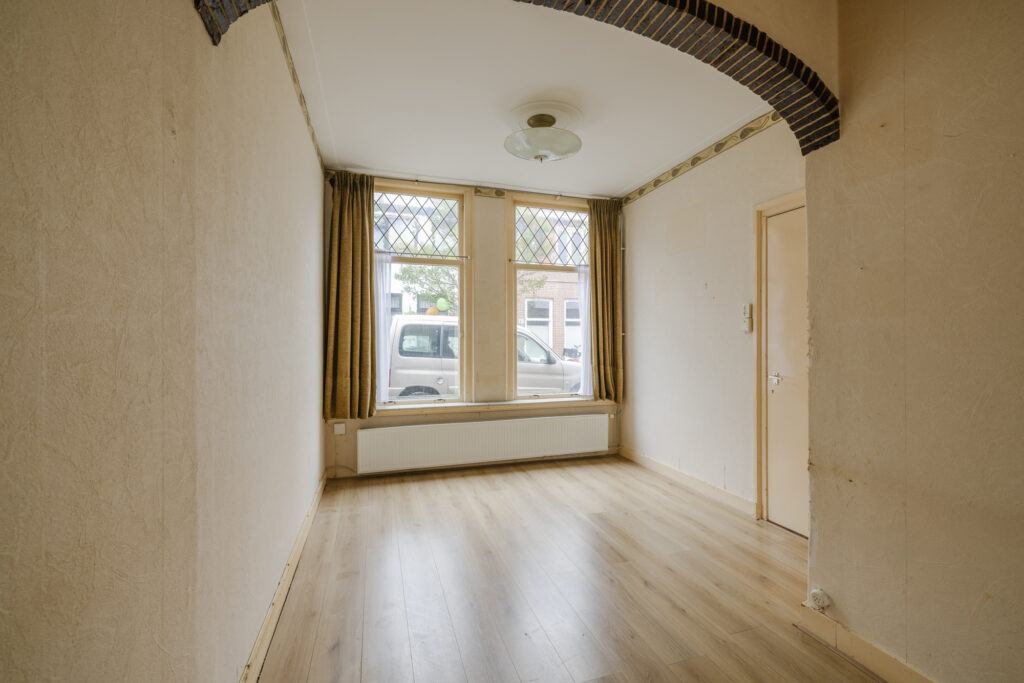 Empty room with wood floor and large windows.