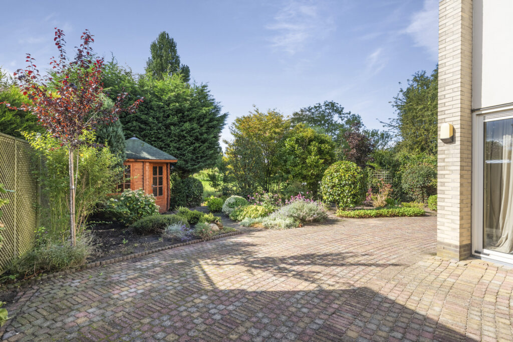 Brick patio with garden and wooden gazebo.