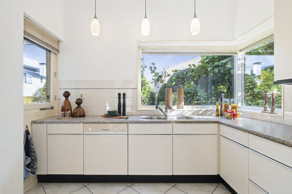 Modern kitchen with large windows and countertop decorations.