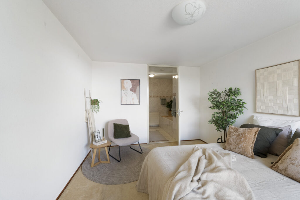 Cozy bedroom with chair and plant decor.
