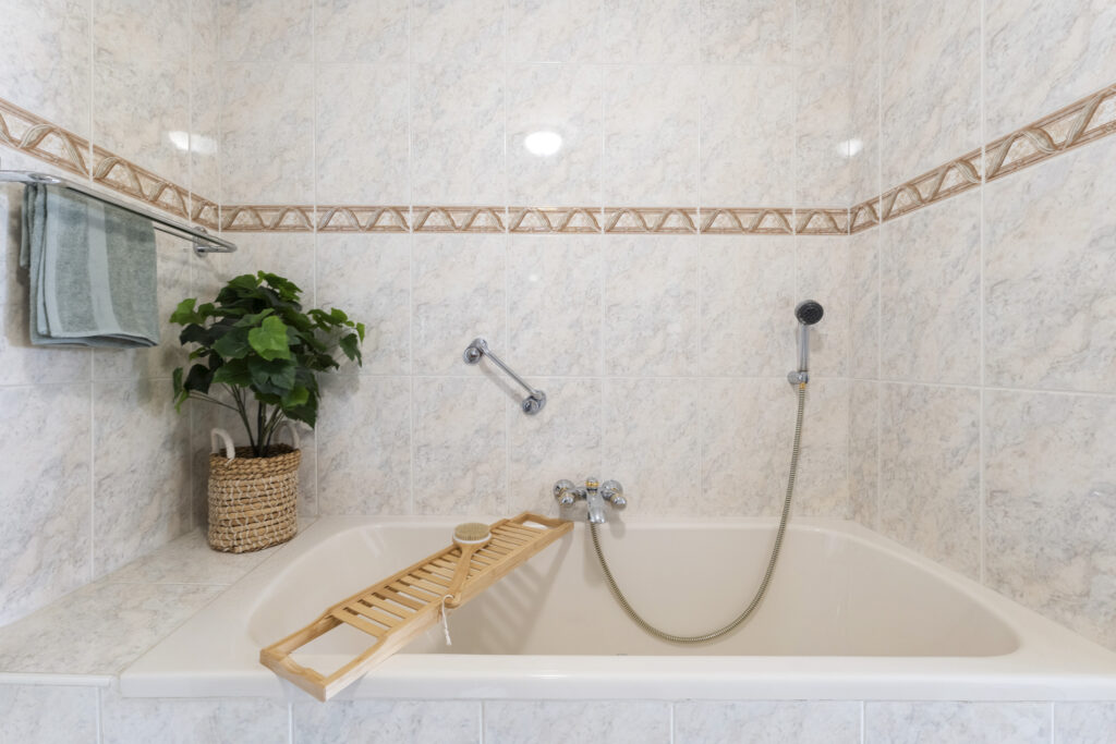 Marble bathroom with bathtub and potted plant.