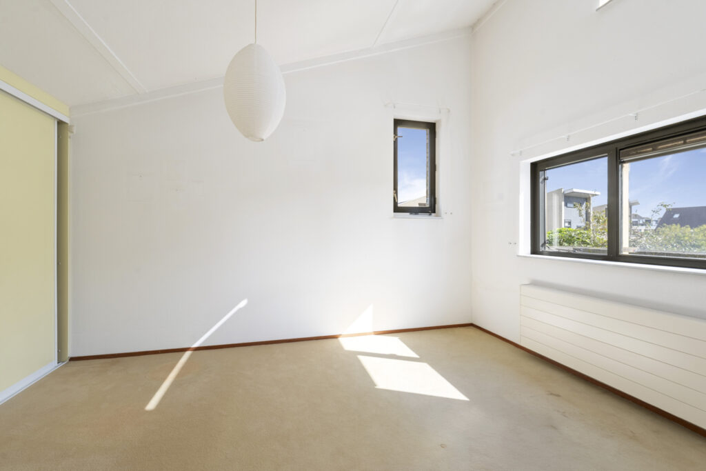 Empty room with windows and hanging light fixture.