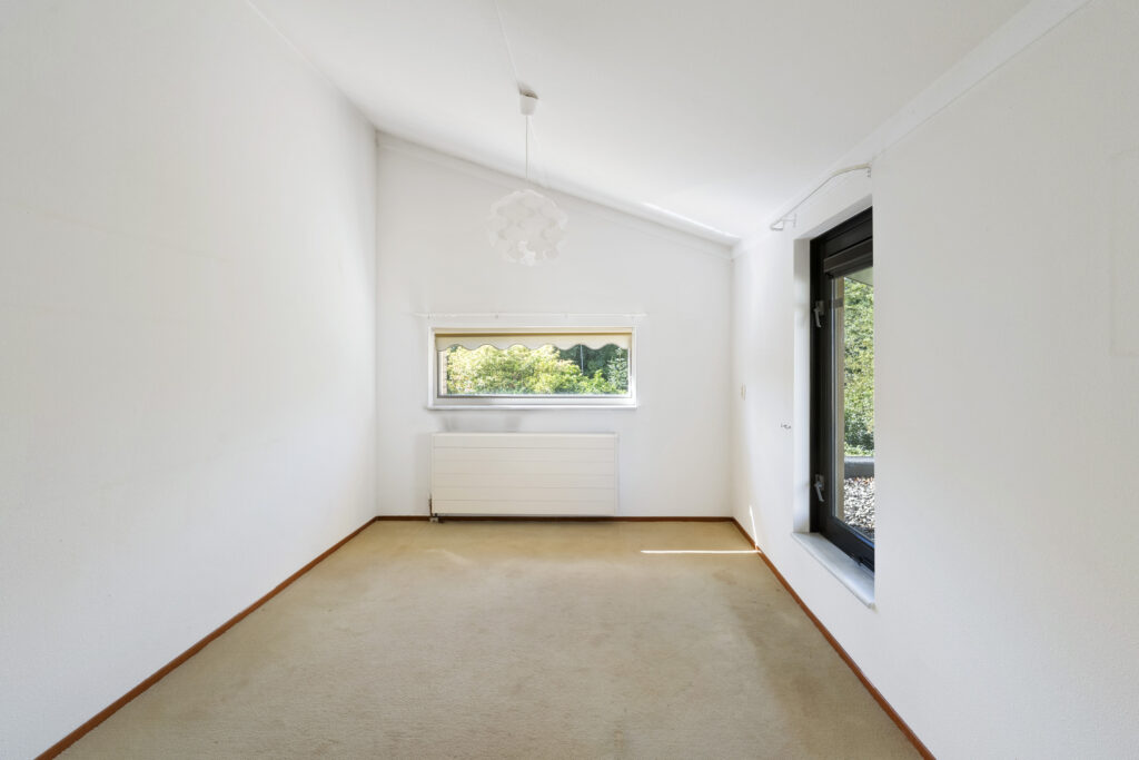 Empty white room with window and beige carpet