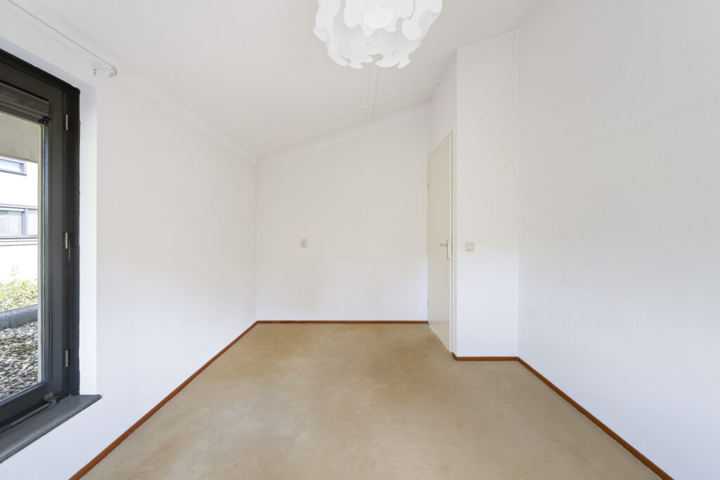 Empty room with white walls and beige carpet.