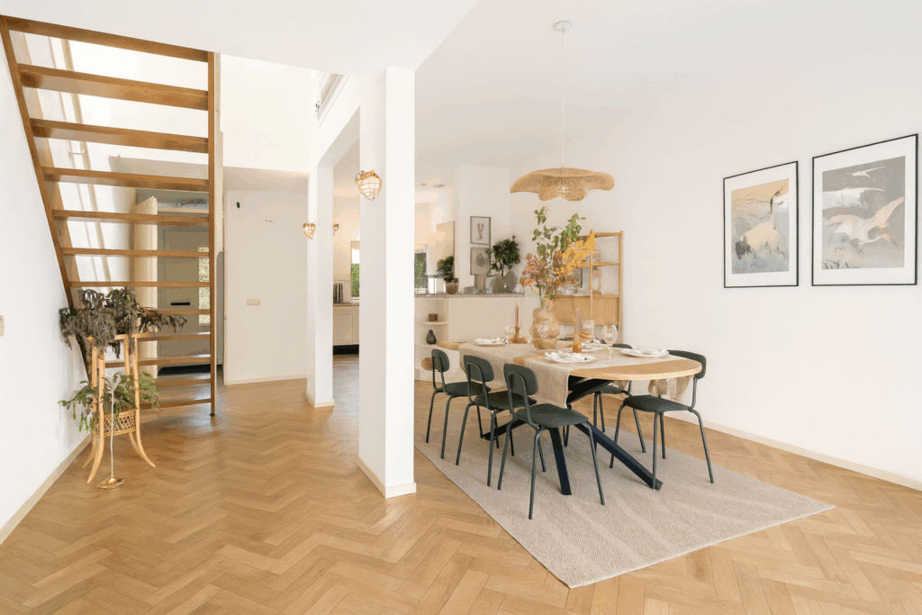 Modern dining room with wooden floor and staircase.
