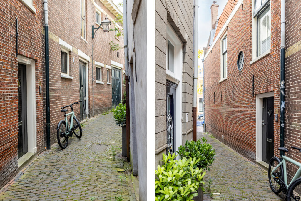 Narrow cobblestone alley with parked bicycle and plants.