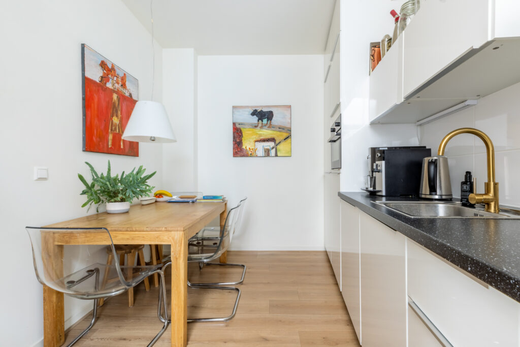 Modern kitchen with wooden dining table and art decor.