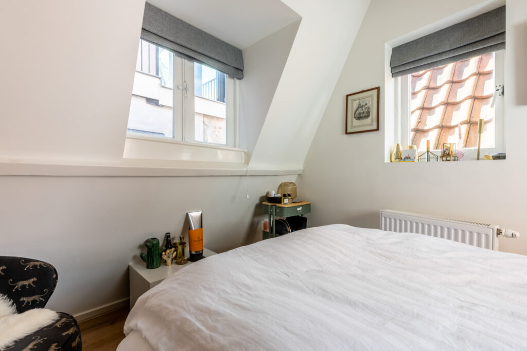 Cozy attic bedroom with window and decor items.