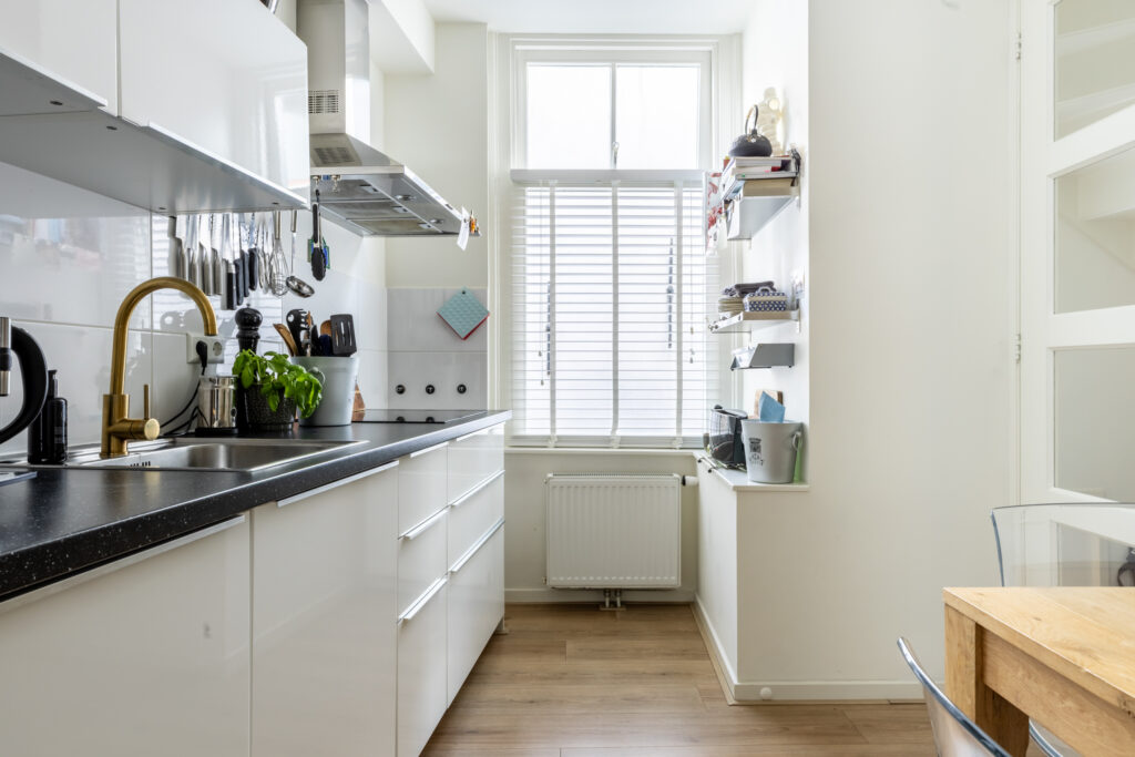 Modern kitchen with white cabinets and natural light.